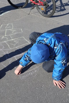 Russia, Severomorsk - 01 May 2018: The boy paints on the asphalt in the spring on the square