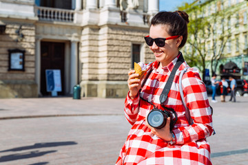 tourist woman with photo camera and ice cream in the middle of european city