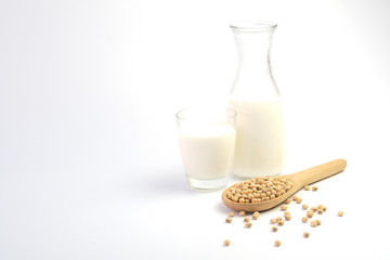 Soy milk in glass and soy beans on white background.