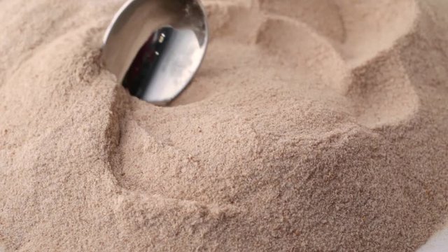 Slow motion video of using a spoon to stir orange flavor psyllium husks then take a spoonful at the end.