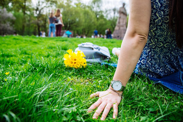 woman sitting on grass in city park with yellow flowers