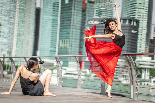 Two beautiful young girls having fun photo shooting on a deck with skyscrapers city background - Powered by Adobe