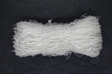 White Rice Noodles Tied with White Rope on Black Stone Background Surface