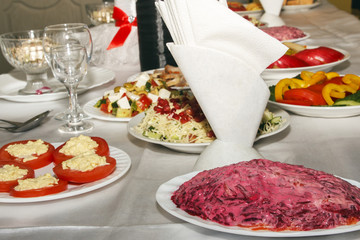 Table served with food and flatware. Banquet table for guests. Empty clean wine glasses and plates with fresh snack on festive table