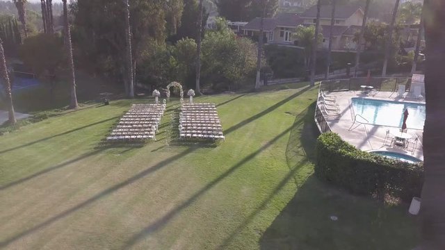 marriage, wedding, drone, aerial, ceremony, bride, groom, chairs, reception, garden, people, palm trees, grass, trees, rice, blue