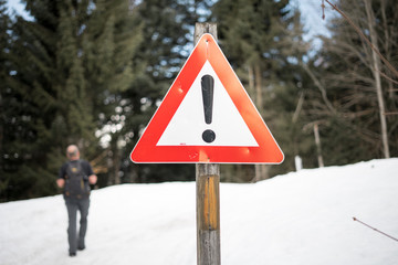 warning sign in a snowy landscape for hiking hiker and outdoor sports, man hiking in background © Karin Martin