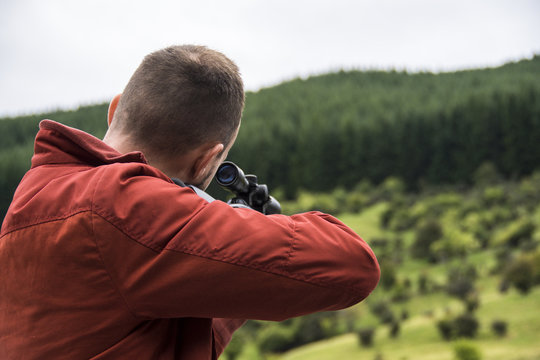 Young man aiming through rifle scope whilst hunting