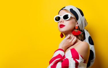 Portrait of beautiful style woman in sunglasses and striped clothes on yellow background