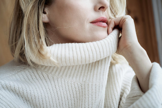 Mid section of woman with white sweater at home