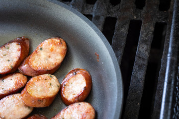 Close up on sliced sausage in a nonstick pan with space for text on the right
