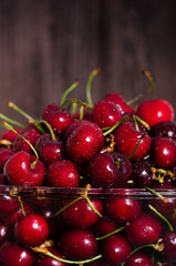 Fresh cherry fruits in a glass on a wooden table. Free space for your text