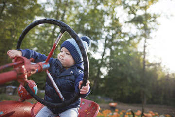 Baby boy sitting on tractor at pumpkin patch