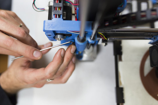 Cropped hands of engineer fixing 3D printer on table