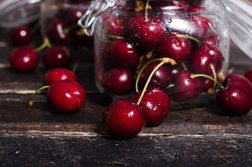 Cherries in glass jar on wooden table. Free space for your text