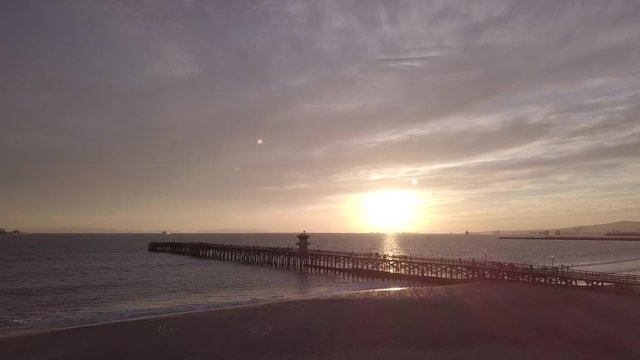 Drone ascending over beach pier durring Sunset