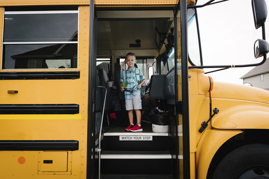 Portrait of boy with backpack standing in school bus