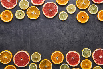 Flat lay of citrus fruits pattern of lemon, orange and grapefruit on black stone background. Copy space in the middle. Top view.