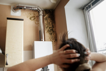 Close-up Of A Shocked Woman Looking At Mold On Wall