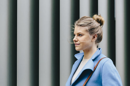 Side view of young woman standing against shutter 