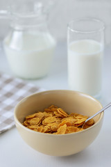 cornflakes with milk in a plate on a white table