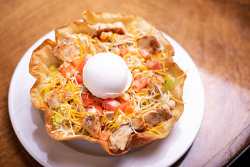 Restaurant taco bowl with scoop of sour cream
