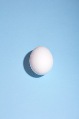 Fototapeta na wymiar white egg with deep shadow on a blue background