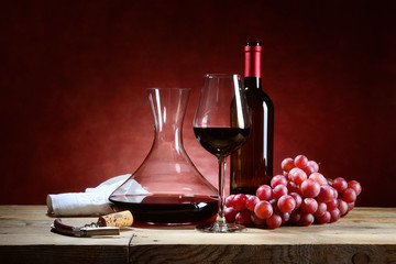 Red wine glass with bunch of grapes and decanter