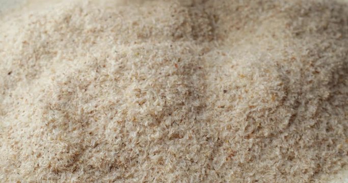 A very close view of pouring psyllium husks onto a white plate.