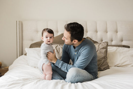 Portrait of cute son with father on bed at home