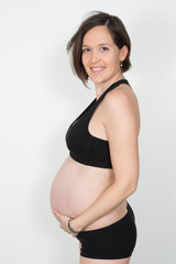 Pregnant woman touching belly looking at camera in sport clothes