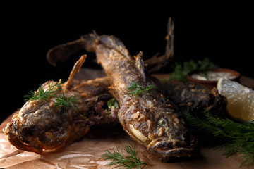 Fried fish goby with sauce on a wooden board