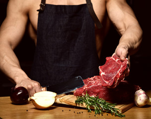 Strong sport man prepare cook beef steak ribs on dark kitchen background healthy eating concept on black 