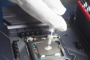 Hands wearing White Gloves with syringe applying thermal paste on the CPU processor on motherboard