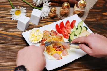 breakfast - bread and butter on a background of scrambled eggs and bacon with tomatoes and cucumbers on a wooden background close-up