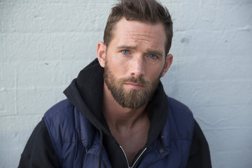 Close-up portrait of serious man standing by wall