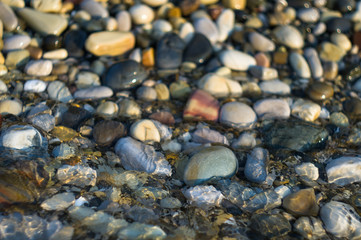 pebble stones on the sea beach, the rolling waves of the sea with foam