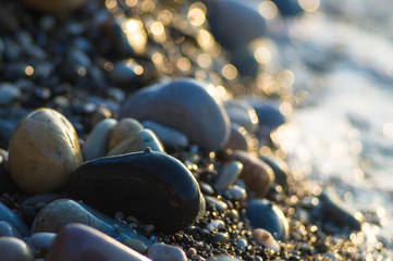 pebble stones on the sea beach, the rolling waves of the sea with foam