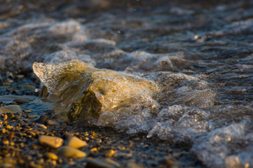 pebble stones on the sea beach, the rolling waves of the sea with foam