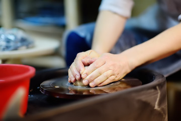 Close-up photo of hands of woman making clay object