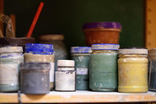 Colorful cans of paint on the shelf in the workshop