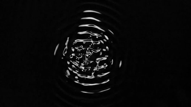 Playing ultrasonic frequencies with water. Black background. Slow motion