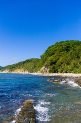 Obraz premium rocky sea shore with pebble beach, waves with foam