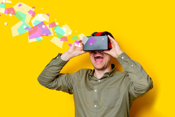 Young man using a VR glasses. Portrait on yellow background