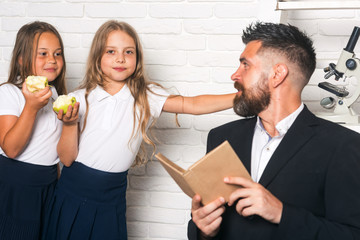 Back to school and home schooling. Literature lesson and reading grammar book. School time of sisters and father in library. Education in knowledge day. Teacher man read story to girls eating apple