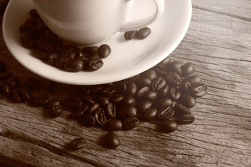 Cup of coffee and coffee beans on wooden floor.