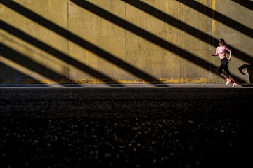 Young fit blonde woman running in the street