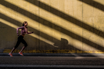 Fototapeta na wymiar Young fit blonde woman running in the street