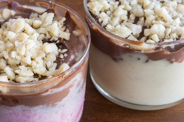 Sweet spoon with two creams and almonds, two desserts in transparent glasses. Close Detail