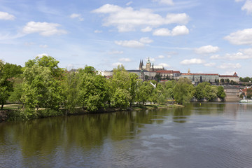 Fototapeta na wymiar Spring green Prague Lesser Town with gothic Castle and Charles Bridge above River Vltava in the sunny Day, Czech Republic