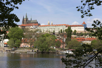 Fototapeta premium Wiosenna zieleń Praga Mała Strana z gotyckim zamkiem nad rzeką Wełtawą w słoneczny dzień, Republika Czeska